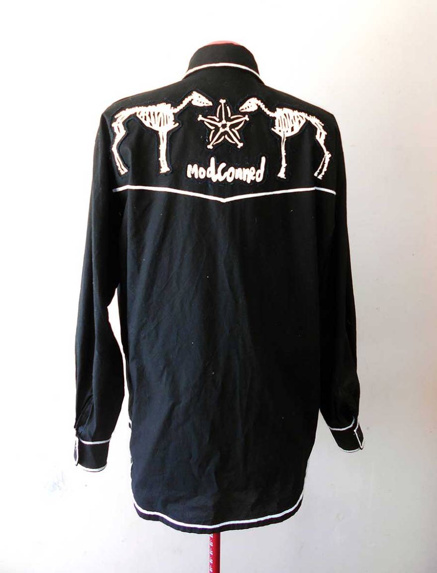 A black cowboy shirt with white piping and decorative motifs screen printed in white ink