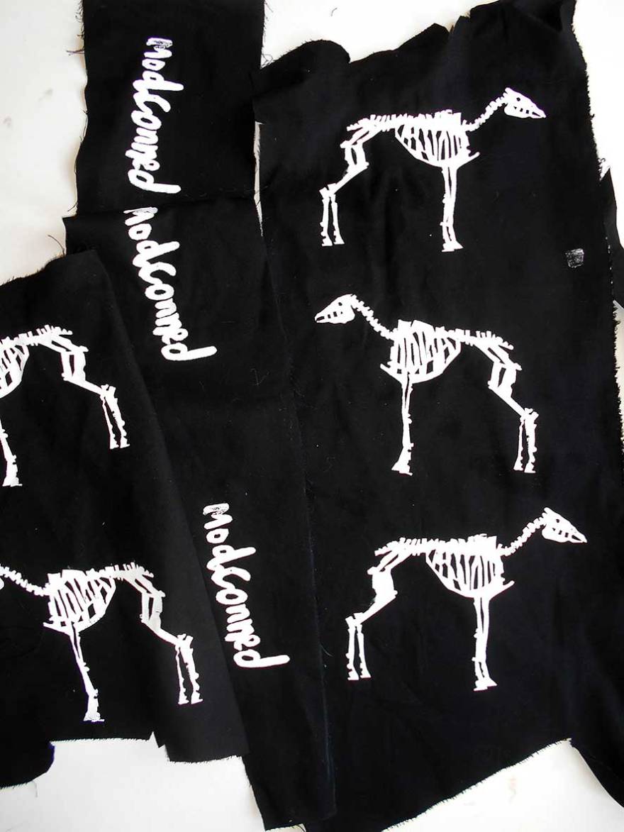 White screen printed motifs of a horse skeleton and the word "modconned"
